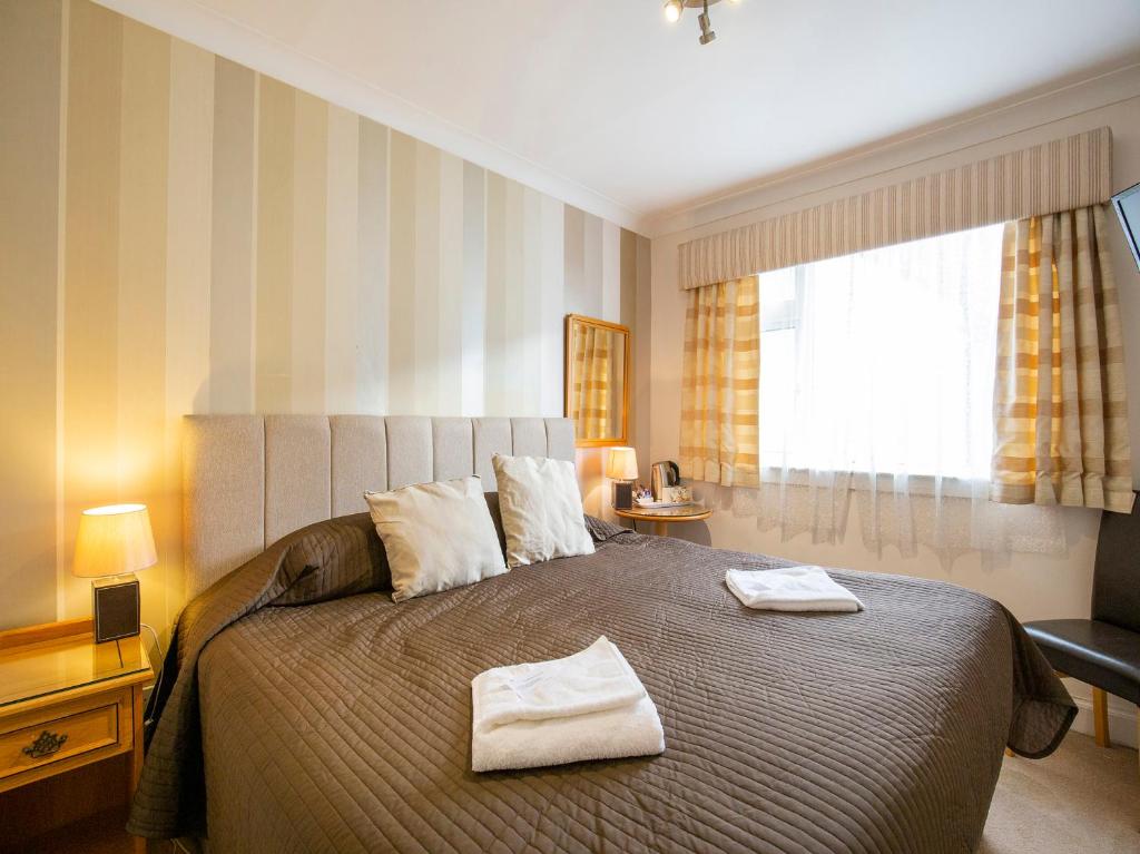 爱丁堡OYO Arden Guest House, Craigmillar Castle Edinburgh的一间卧室配有一张大床和两条毛巾