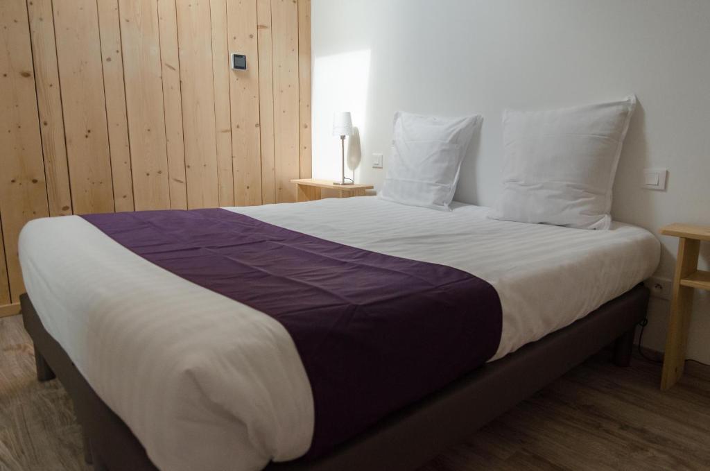 BenfeldSuites Conviviales la Vignette的一间卧室配有一张大床,铺有紫色和白色的床单。