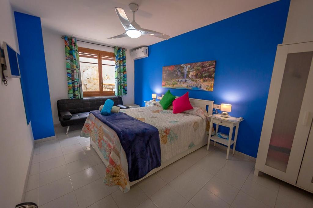 卡迪瓦Casa Camino al Castillo的一间卧室设有蓝色的墙壁和一张带色彩缤纷枕头的床。