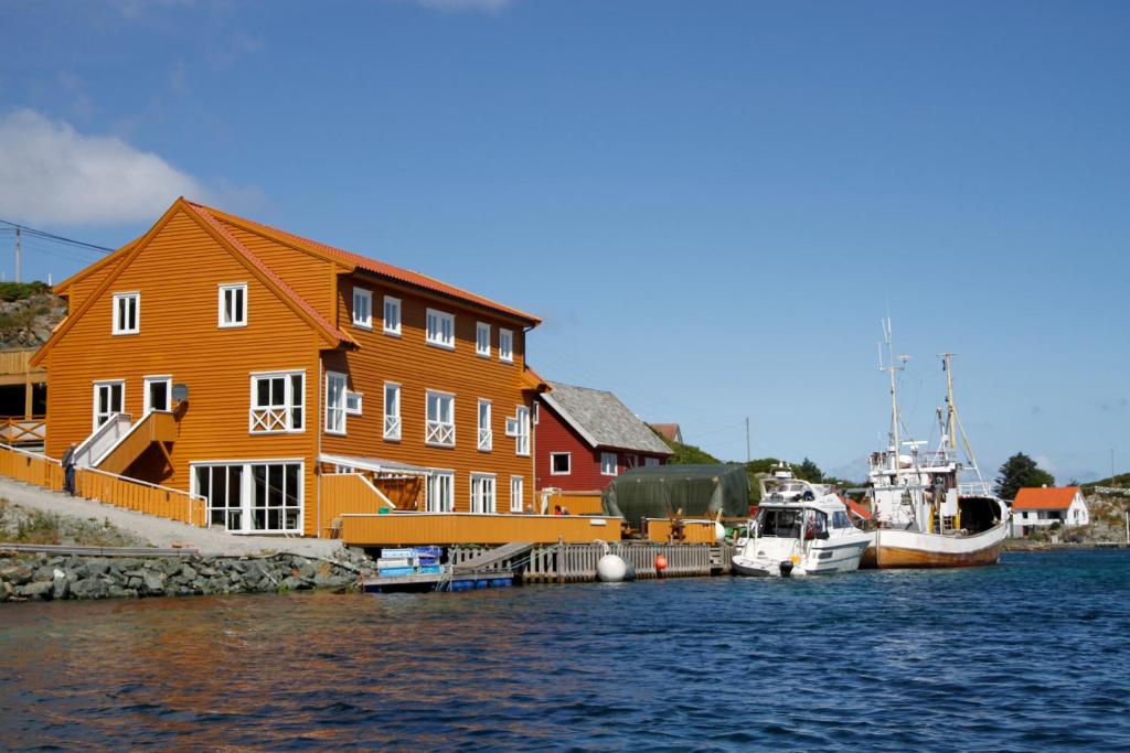 RøværRøvær KulturHotell的一座大型的橙色建筑,在水中划船