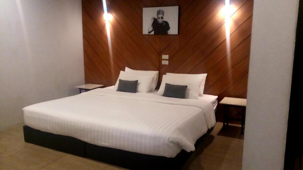 清迈罗德曼酒店的卧室配有一张白色大床和木墙