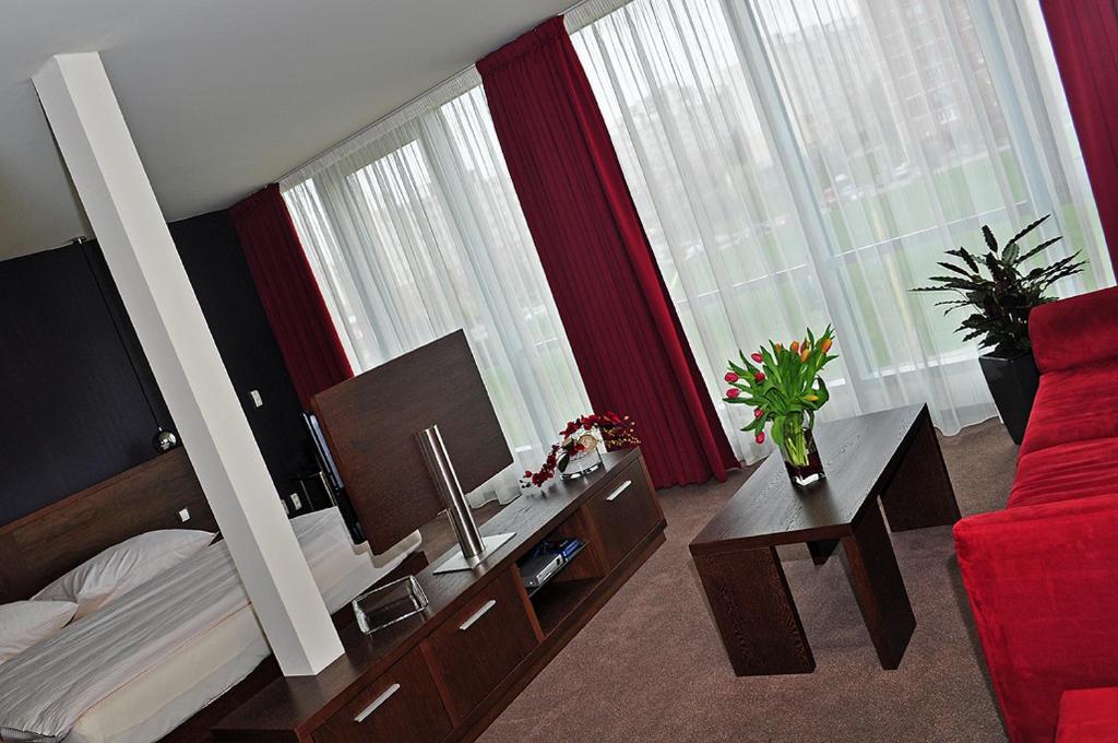 科希策Glass House Kosice的酒店客房,配有一张床和一张红色的沙发