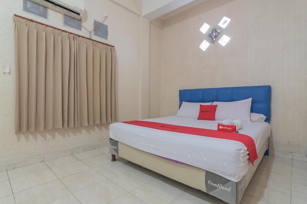 巴厘巴板RedDoorz Syariah near Terminal Batu Ampar 2的一间卧室配有一张大床和蓝色床头板