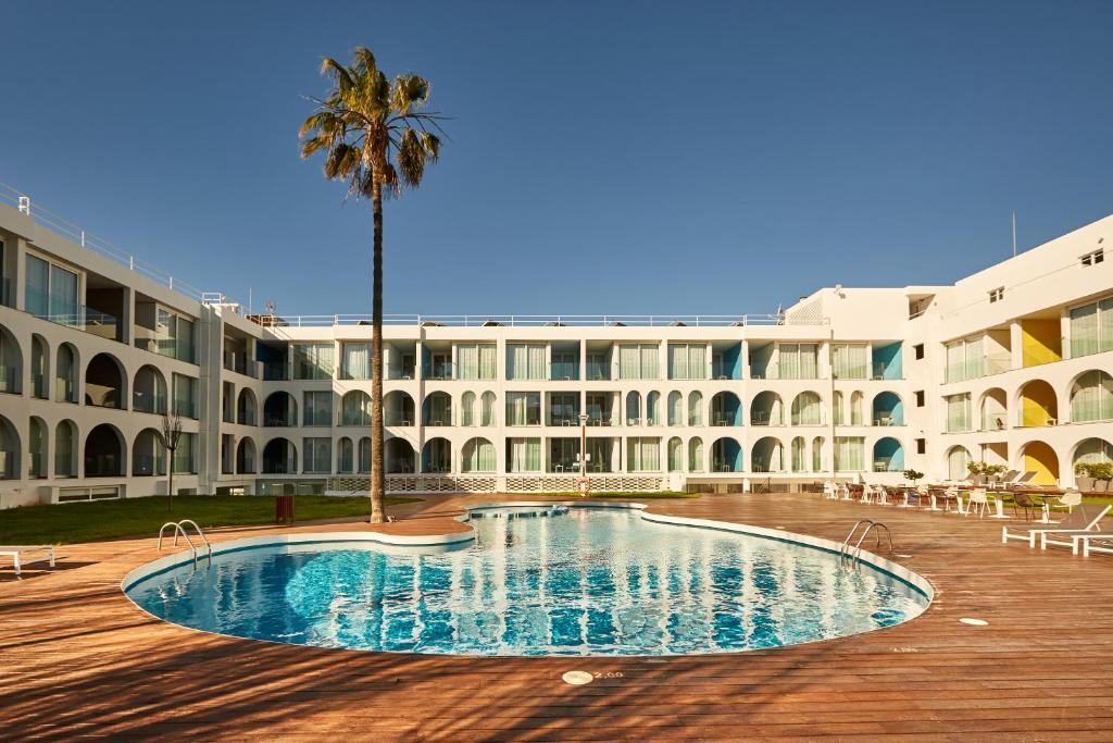 普拉亚登博萨Ebano Hotel Apartments & Spa的一座棕榈树大建筑和一个游泳池