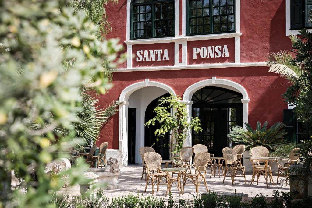 阿莱奥尔Santa Ponsa Fontenille Menorca的一座红色的建筑,前面设有桌椅