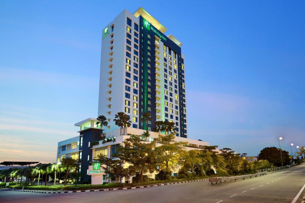 马六甲马六甲假日酒店的一条街道前方有棕榈树的高楼