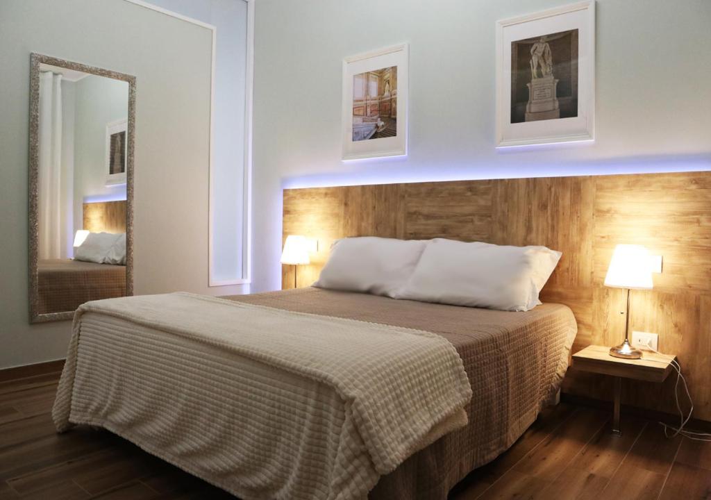 卡塞塔Residenza La Reggia的一间卧室配有一张带两盏灯和镜子的床