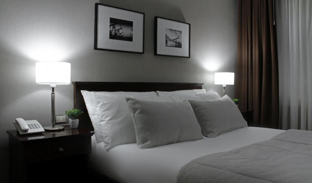 布宜诺斯艾利斯十月8日酒店的一间卧室配有一张带两盏灯的床和一部电话