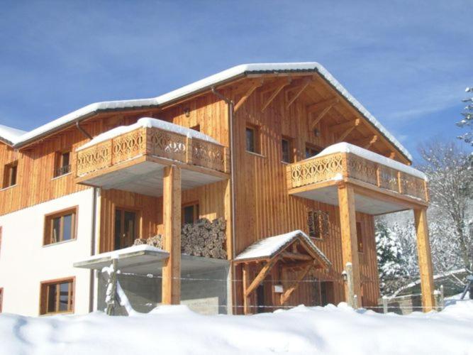勒梅尼勒Comfy chalet with a dishwasher, in the High Vosges的一座大型木制建筑,在雪地里设有两个阳台