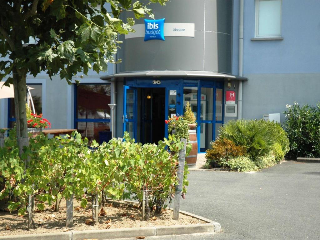 利布尔讷利布尔讷宜必思快捷酒店的一栋带蓝色门和灌木丛的办公楼