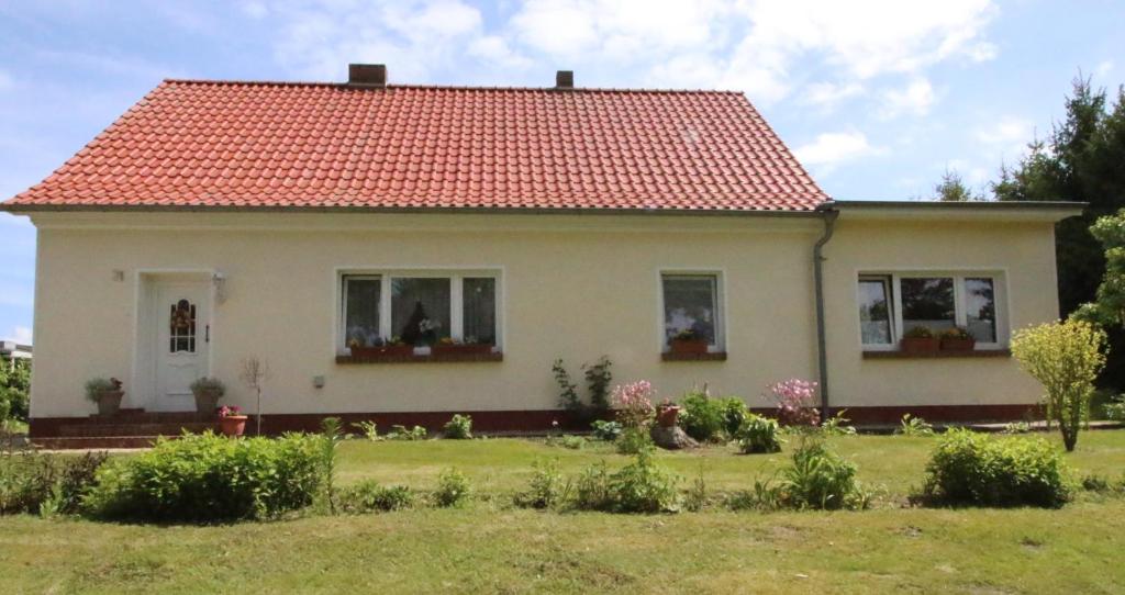 BartelshagenFerienwohnung An den Tannen的一间白色的小房子,有红色的屋顶