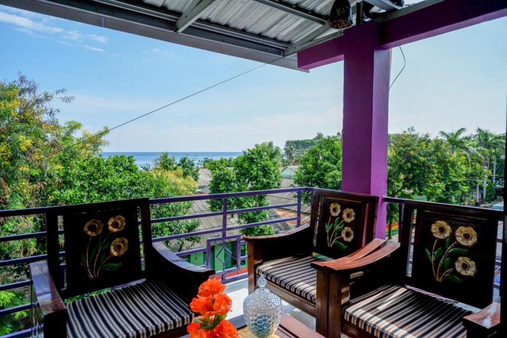 MajeneRedDoorz @ Hotel Aulia Majene的阳台设有2张长椅,享有海景。