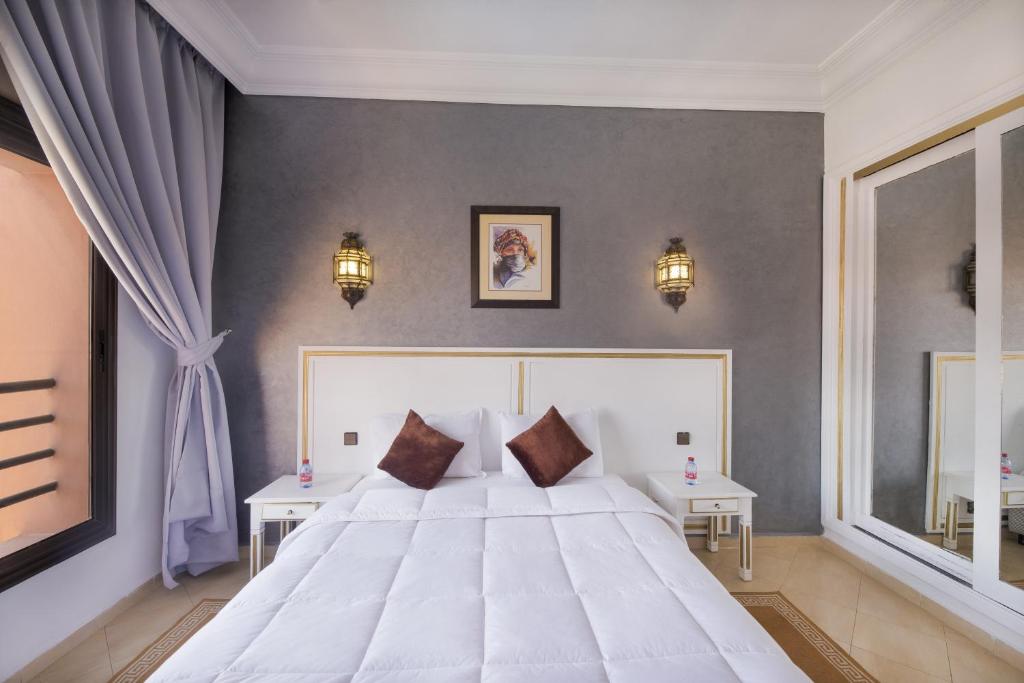 马拉喀什莫加多尔门扎公寓酒店的卧室配有一张白色的大床和两张桌子