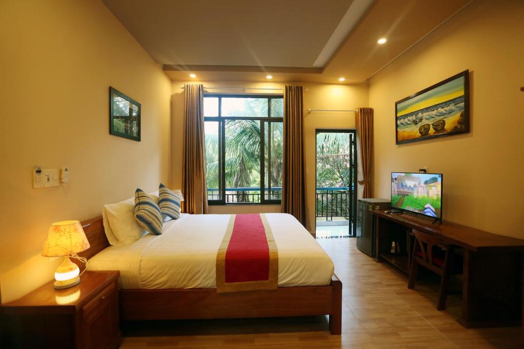 An Bàn (2)Tan Doan An Bang center beach villas的一间卧室设有一张床、一台电视和一个窗口。