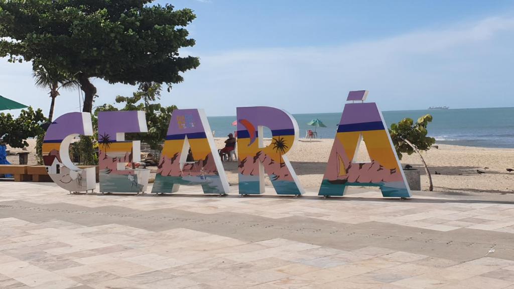 福塔莱萨APTO LUXO EM HOTEL - BEIRA MAR FORTALEZA的海滩上的标志,以海洋为背景