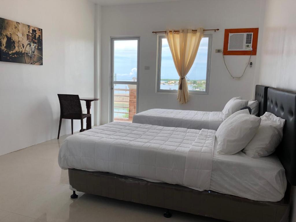 MayaArriyus Apartelle的一间卧室设有两张床、一把椅子和一个窗户。