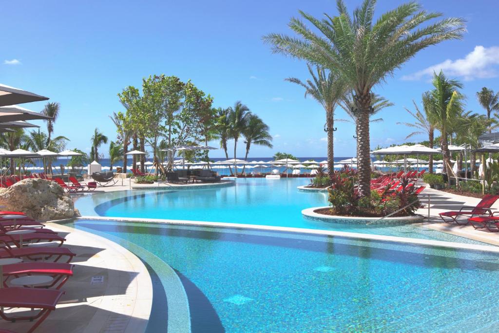 西湾Kimpton Seafire Resort + Spa, an IHG Hotel的一座带椅子和棕榈树的度假村游泳池