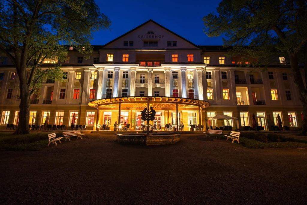 巴特利本施泰因凯瑟霍夫文化酒店的一座大型建筑,在晚上有长椅在前面