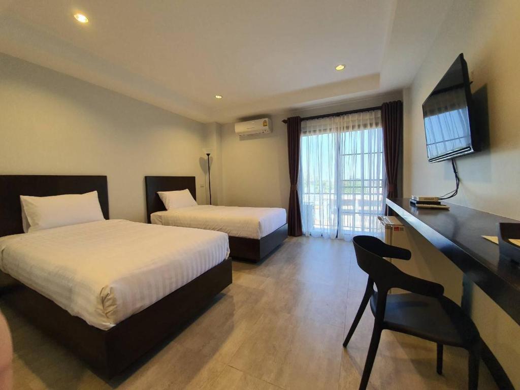 乌隆他尼T-NEE Hotel@Udon的酒店客房设有两张床、一张桌子和一台电视。