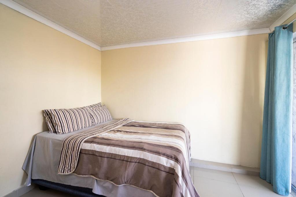 开普敦Hasate Guest House 10 Florence street Oakdale Belliville 7530 cape town south African的一间卧室配有一张带毯子的床和窗户
