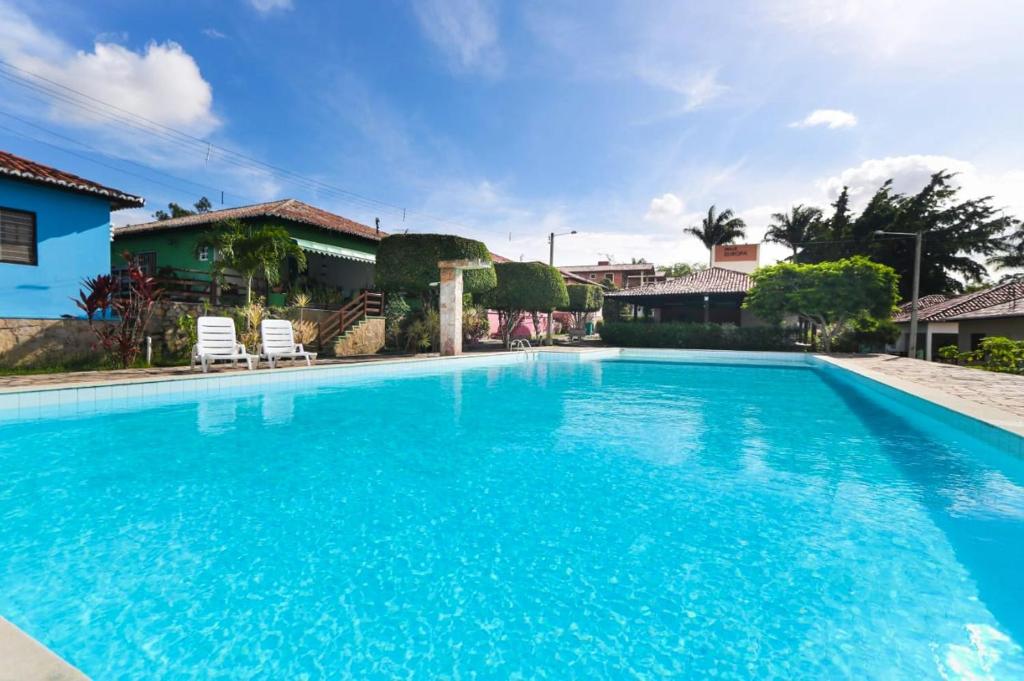 格拉瓦塔Lindo Privê 04 Suítes com AR, 5WC e Grande Piscina的庭院里的一个蓝色海水大型游泳池