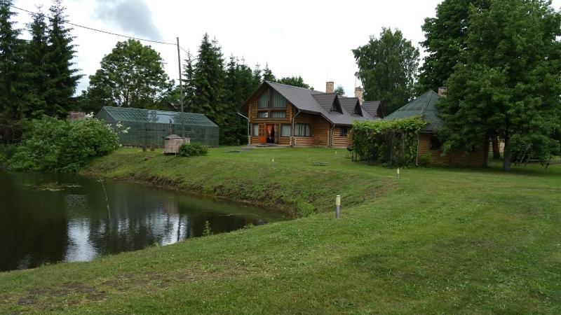 叶尔加瓦Upeslīči atpūtai的前面有一条河的木屋