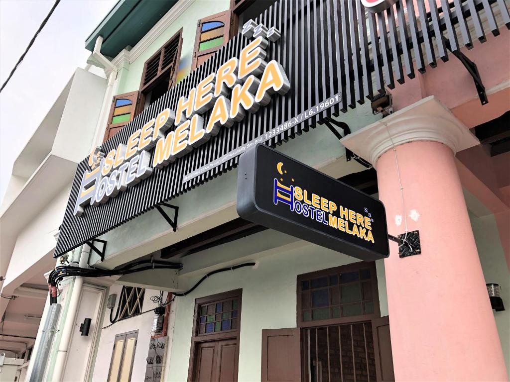 马六甲Sleep Here Hostel, Melaka的建筑物一侧的标志