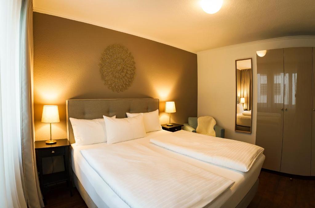 弗莱堡拉蓬蒙斯特广场酒店的一间卧室配有一张带两盏灯的大型白色床。