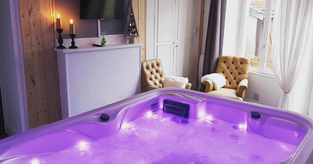 肖蒙Suite EDEN avec jacuzzi privé的一个带两把椅子的房间的紫色浴缸