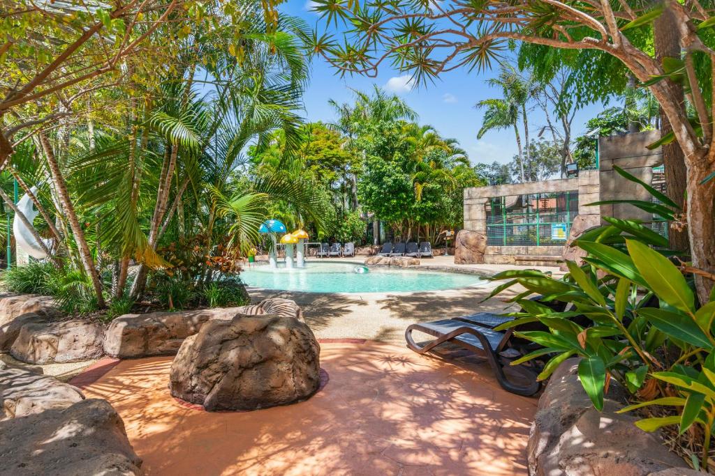 黄金海岸阿什莫尔棕榈度假村的一座拥有树木和岩石的度假村内的游泳池