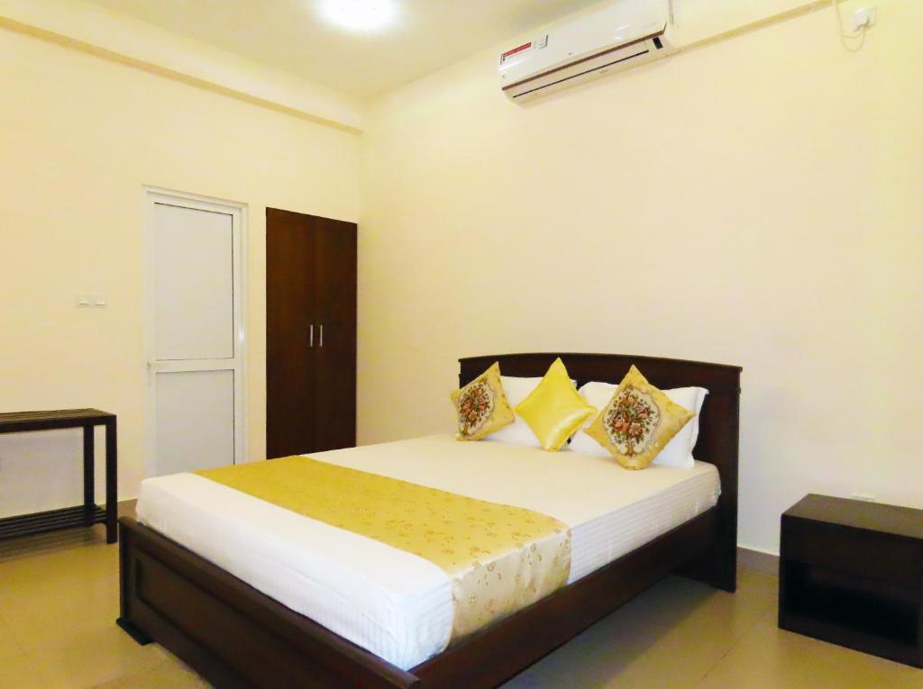 科伦坡VIVAS Residencies Luxury Apartments的一间卧室配有带白色床单和黄色枕头的床。