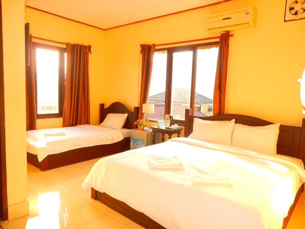万荣Vang Vieng Camellia Hotel的酒店客房设有两张床和窗户。