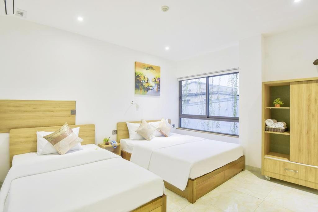 岘港Annie Danang Hotel & Apartment的一间卧室设有两张床和窗户。