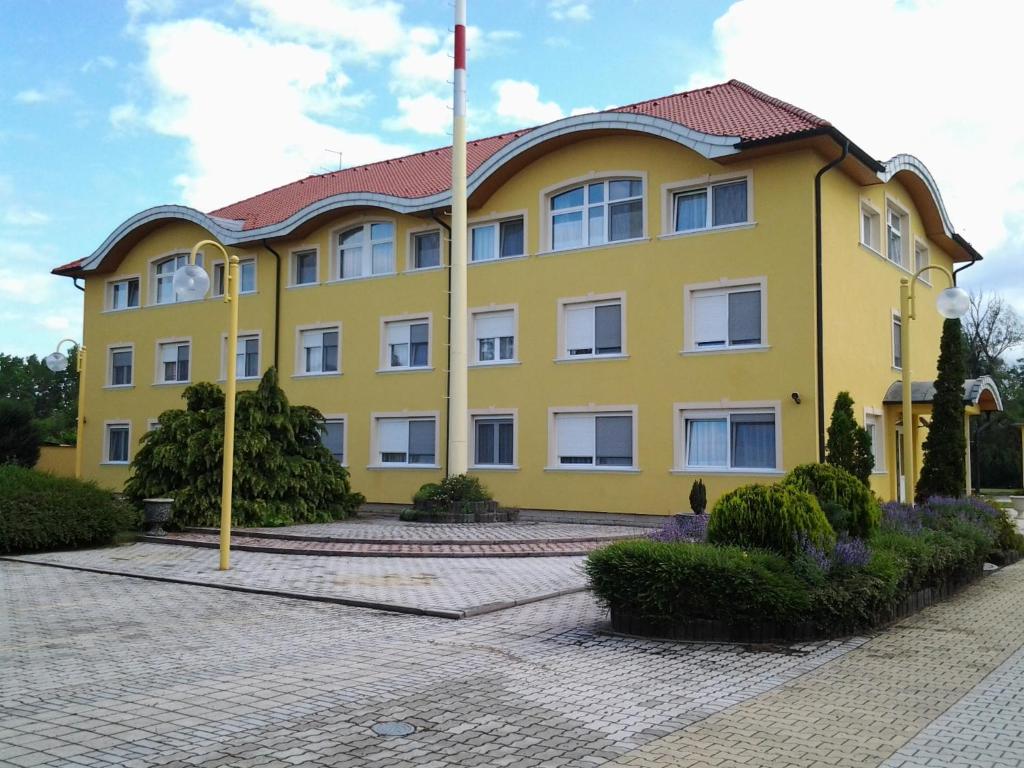 Gönyů莱尔商务酒店的黄色建筑,有红色屋顶