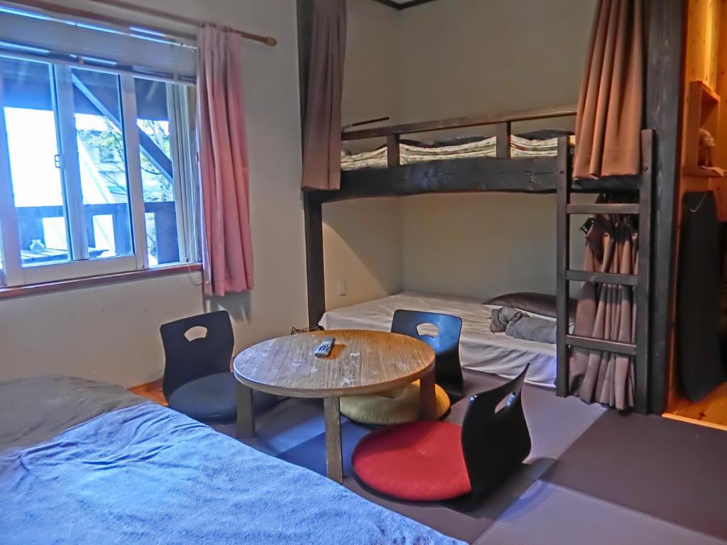 白马村白马 风之子旅馆的客房设有两张双层床和一张桌子及椅子。