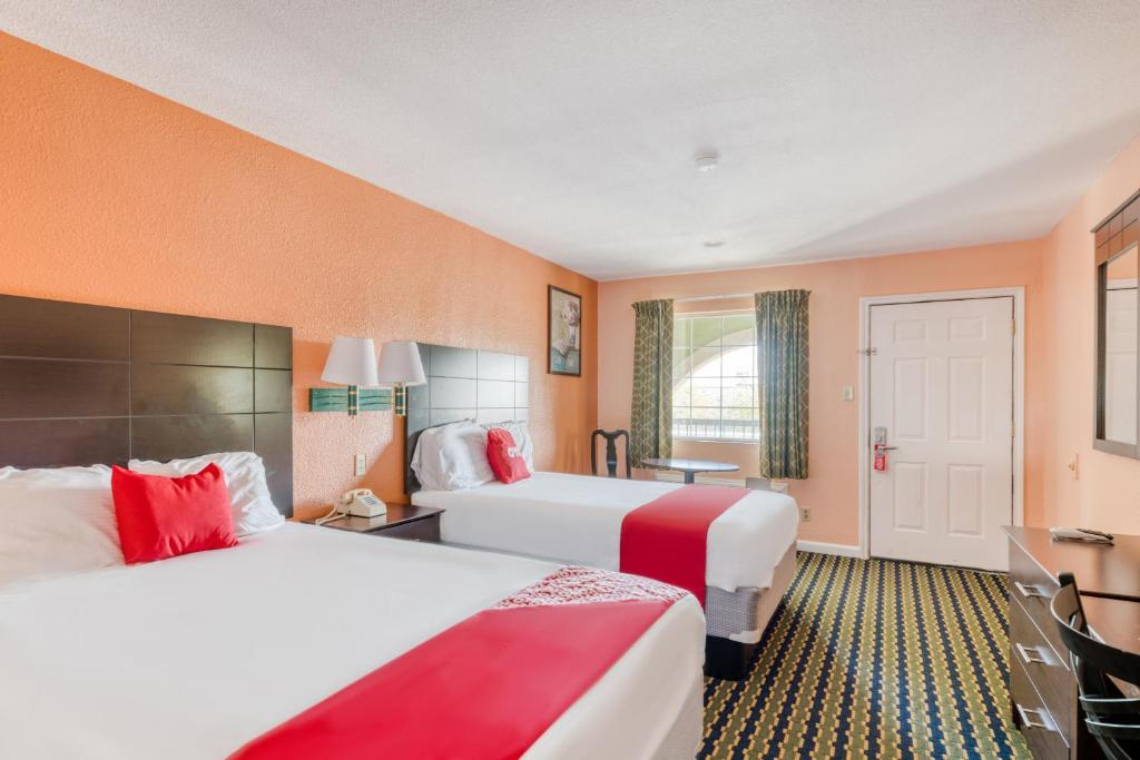 钱诺夫OYO Hotel Channelview I-10的橙色墙壁的酒店客房内的两张床