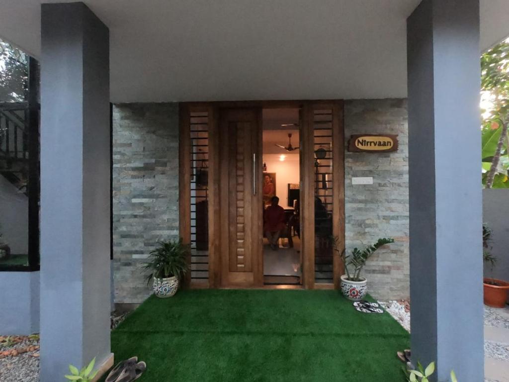 瓦尔卡拉Nirrvaan homestay的一座带绿色草坪的房屋的前门
