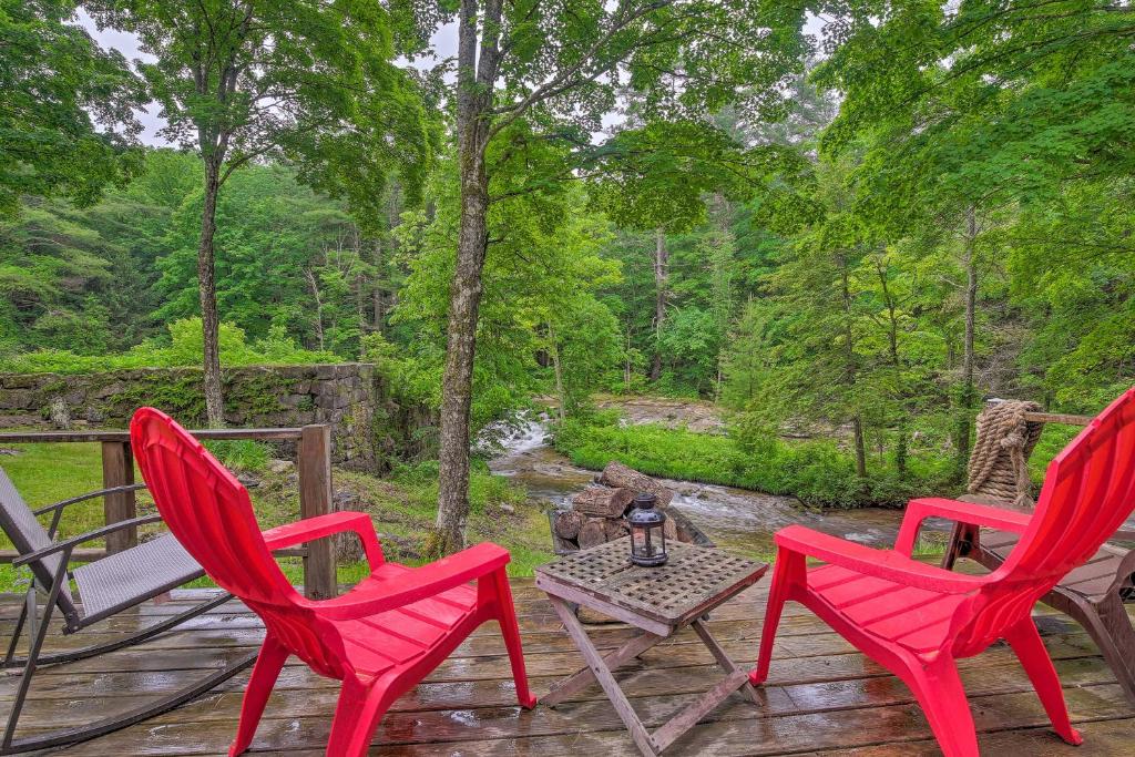 Mill RiverThe Mill River Cabin with Fireplace and River View!的甲板上配有3把红色椅子和一张桌子