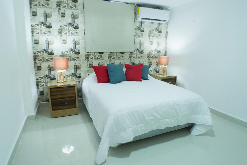 圣多明各Malecon Premium Rooms & Hotel的一间卧室配有白色的床和红色和蓝色枕头