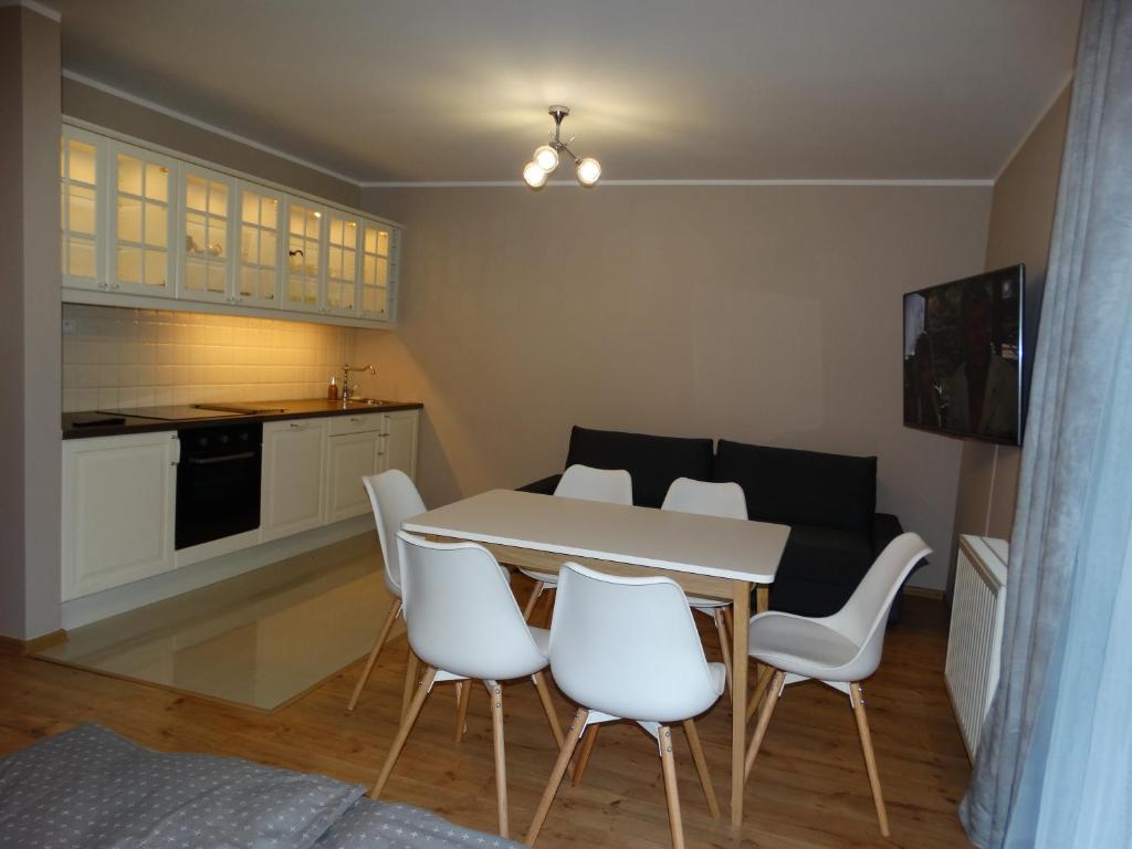 克雷尼察Apartamenty Miku的厨房以及带桌子和白色椅子的用餐室。