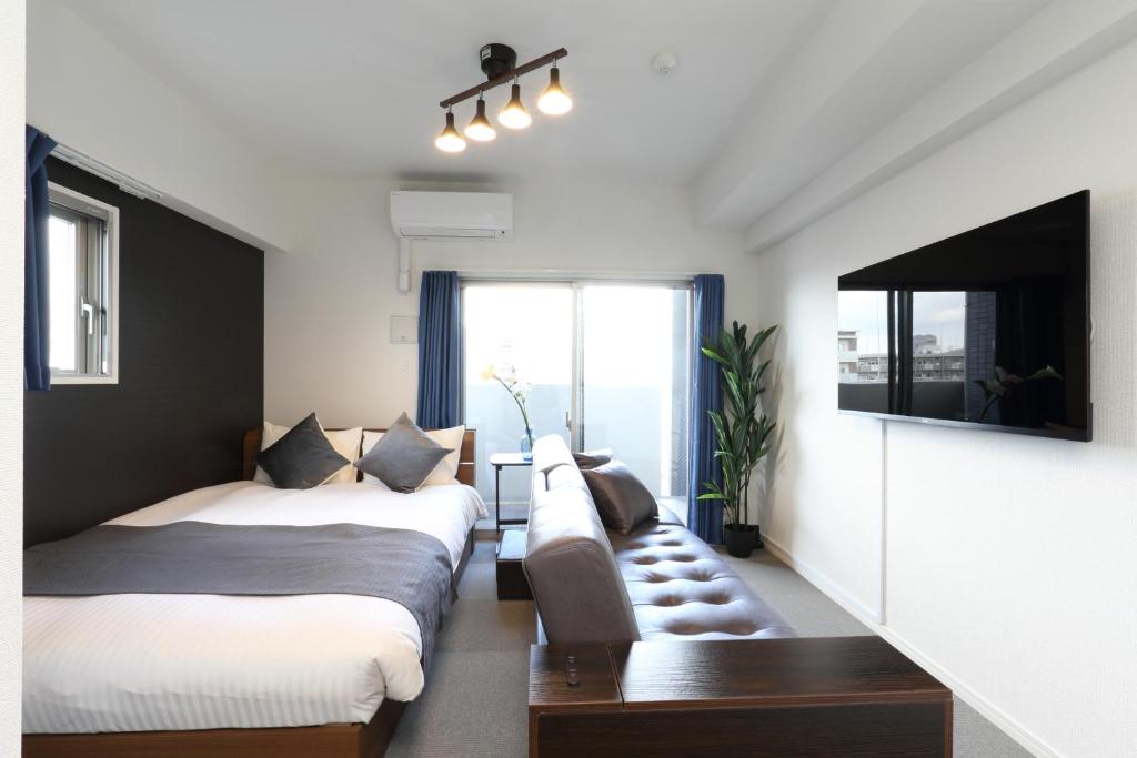 福冈The Grand Residence Hotel Hakata的一张沙发和一台电视机的客房内的两张床