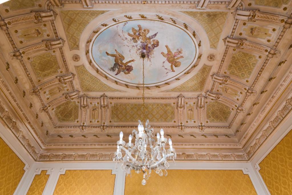 卡塔尼亚Palazzo Arcidiacono - luxury holidays的天花板上挂有吊灯和绘画作品