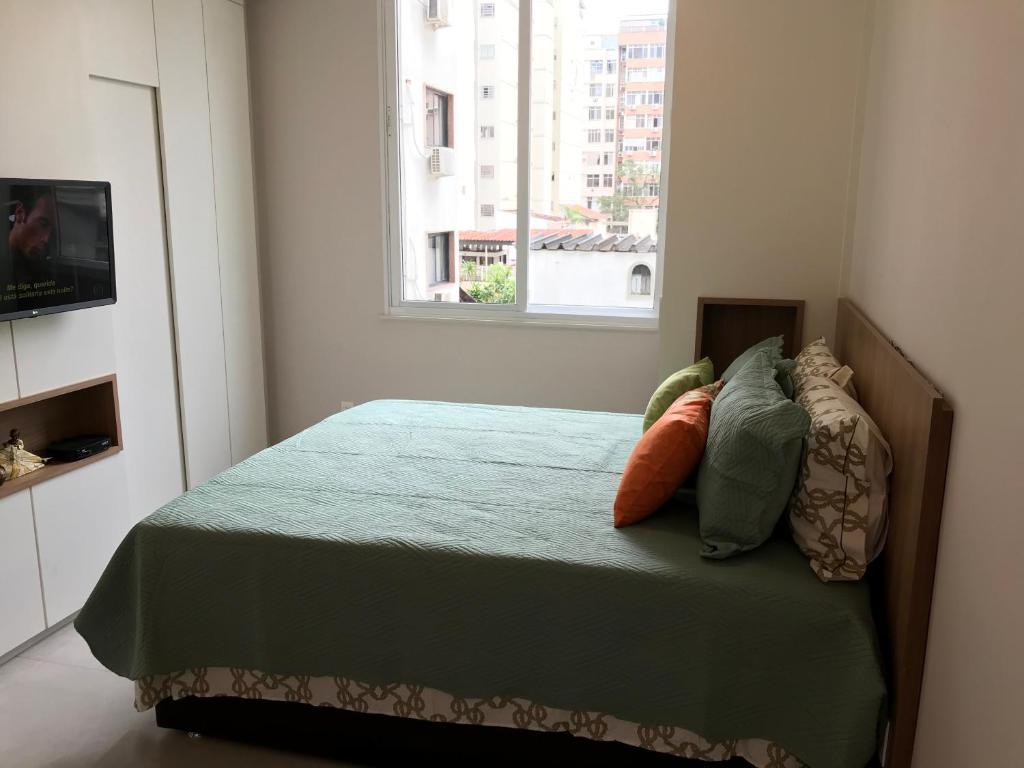 里约热内卢Fantástico STUDIO DIVISA COPACABANA IPANEMA REFORMADO E DECORADO的卧室配有带枕头的床铺和窗户。