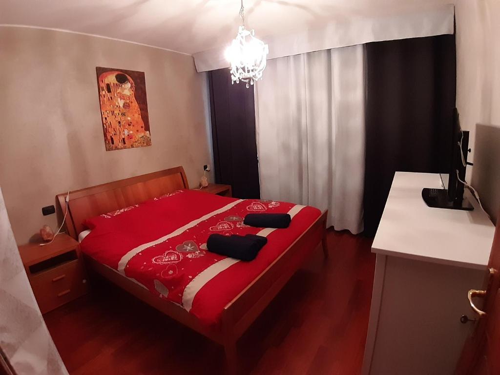 蒙克拉西科Appartamento a Dimaro in Val di Sole的一间卧室配有一张红色的床和吊灯
