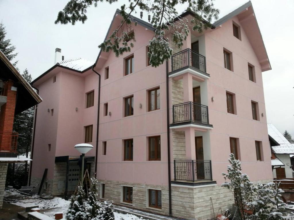 兹拉蒂博尔Vila Meridijan的粉红色的建筑,地面上积雪