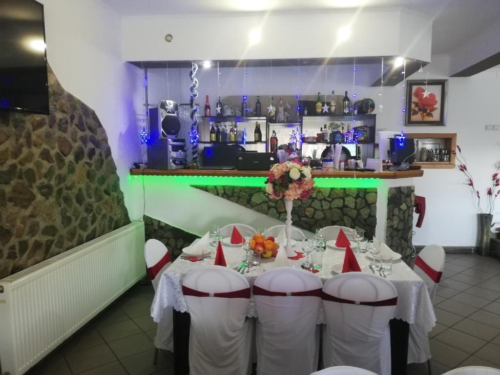 巴亚德菲耶尔Restaurant Vi La Maria的一间用餐室,配有一张带白色椅子的桌子和一间酒吧