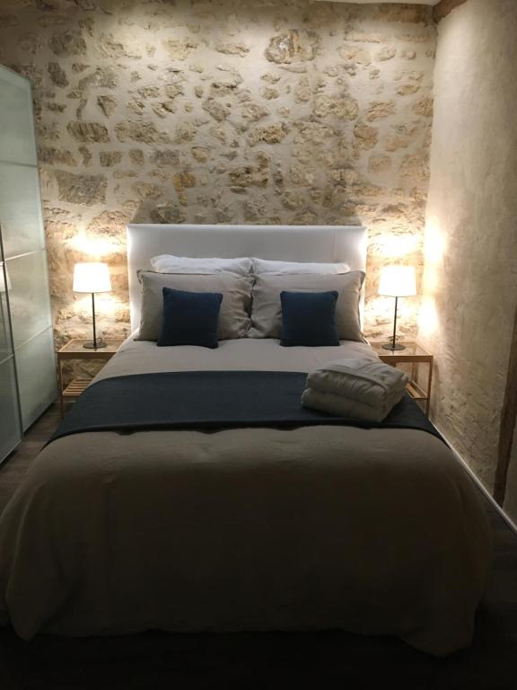 尚蒂伊Le Petit Hameau de Chantilly - Studio Chic et Charme au Coeur de Chantilly - Classé 3 étoiles的一间卧室配有一张带两盏灯的大型白色床。