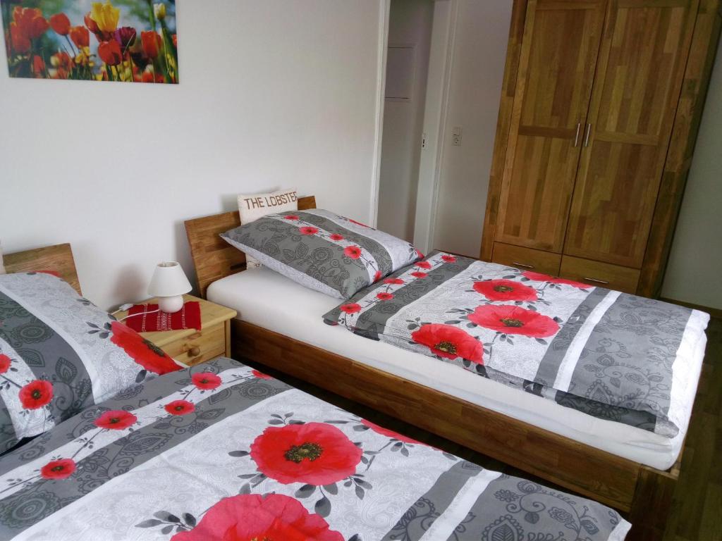 萨克森自由州诺伊斯塔滕Ferienwohnung Familie Schneider的两张床位于带红色鲜花的房间