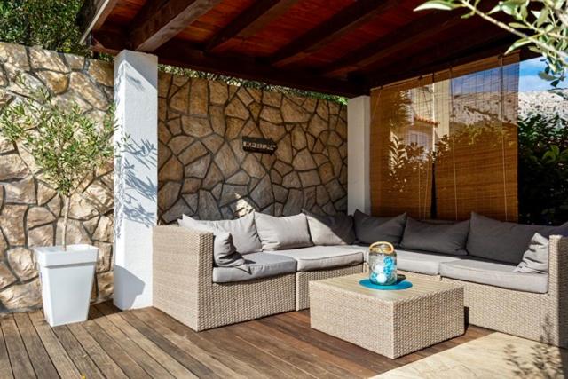 巴斯卡Apartments Adria Garden的一个带柳条家具和石墙的庭院