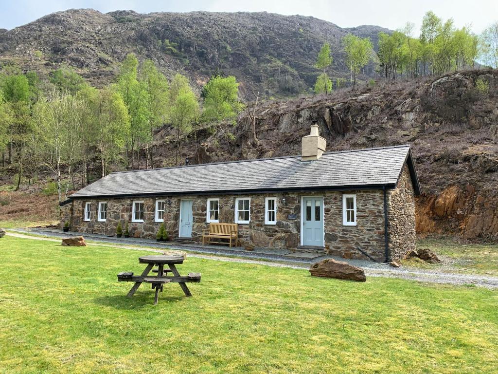 贝德格勒特Sygun Cottage - Detached Cottage in the heart of the Snowdonia National Park的石头小屋前面设有野餐桌